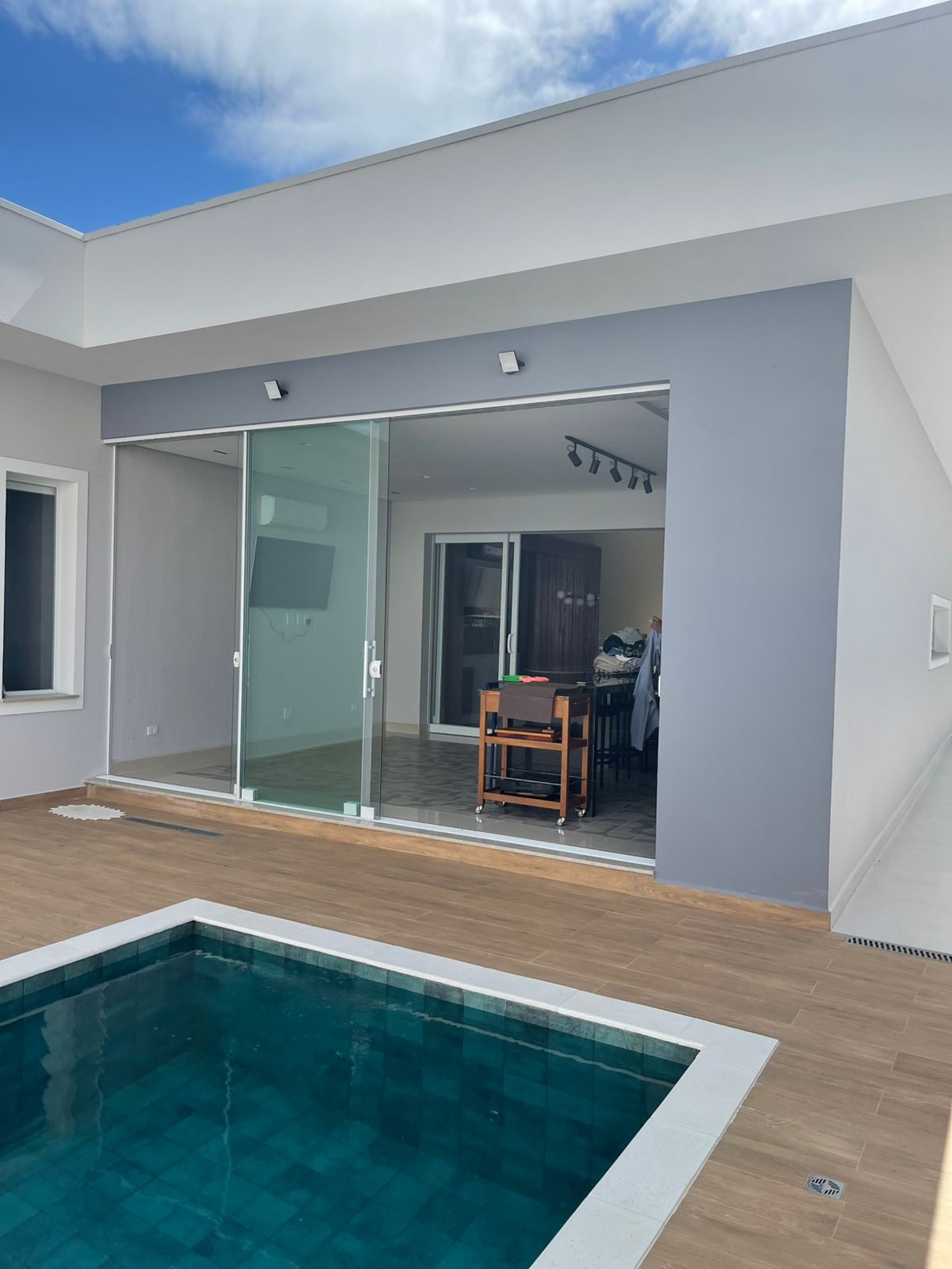Portas de vidro de correr conectando sala e área da piscina